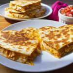Two halves of golden-brown Heart-Shaped Chicken Quesadillas showing shredded chicken and melted cheese filling.