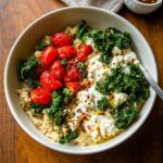 Bowl of High-Protein Savory Overnight Oats topped with roasted cherry tomatoes, kale, and ricotta cheese.