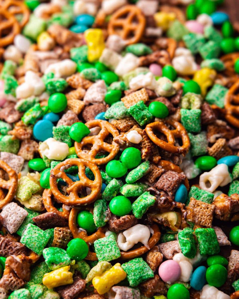 A vibrant, close-up view of the Leprechaun Bait Snack Mix featuring pretzels, green-coated cereal, and candy pieces.