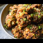 A close-up of several perfectly formed Louisiana Dirty Rice Bites garnished with fresh green onions.
