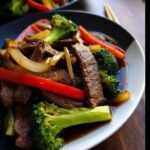 Close-up of a serving of Low Carb Beef Stir Fry featuring sliced beef, bright green broccoli florets, red bell peppers, and onions in a savory sauce.