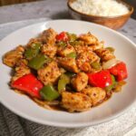 A plate of colorful Low Carb Chicken Stir Fry featuring chunks of chicken, red and green bell peppers, and sesame seeds.