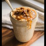 Close-up of Maple Brown Sugar Overnight Oats topped with nuts and drizzled with syrup in a glass jar.