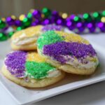 Close-up of frosted Mardi Gras Sugar Cookies decorated with purple, green, and gold sprinkles.