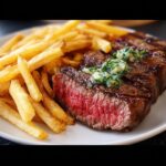 Close-up of a perfectly cooked, medium-rare steak served with golden french fries, ideal for a Romantic Steak Dinner for Two.