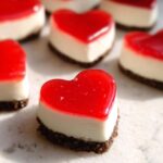 Close-up of a single, perfectly formed Mini Heart-Shaped Strawberry Cheesecake with a bright red jelly topping.