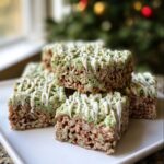 A stack of homemade Mint Chocolate Chip Rice Krispie Treats topped with white chocolate drizzle.