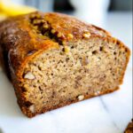 Close-up of a freshly baked loaf of No Sugar Added Banana Bread, showing a moist crumb and walnut pieces.
