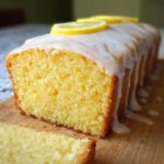 Close-up of a moist One-Bowl Lemon Snack Bread loaf, drizzled with white glaze and topped with lemon slices.