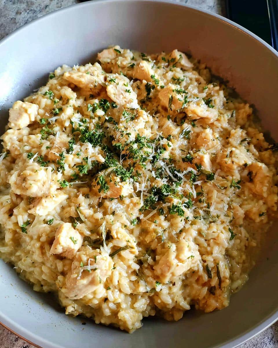 Close-up of a bowl filled with One-Pan Creamy Chicken Rice, topped with fresh parsley and grated cheese.