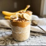 Close-up of Peanut Butter Banana Overnight Oats topped with sliced bananas and peanut butter.