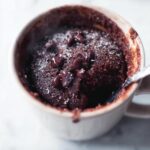 Close-up of a rich Chocolate Mug Cake (5 Minutes) topped with chocolate chips and powdered sugar.