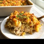 A close-up serving of Rotisserie Chicken Stuffing Bake showing shredded chicken and a crispy, golden topping garnished with fresh thyme.