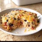 A scoop of creamy Santa Fe Chicken Casserole topped with melted cheddar and black beans.
