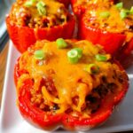 Close-up of a baked Santa Fe Chicken Stuffed Pepper topped with melted cheddar cheese and green onions.