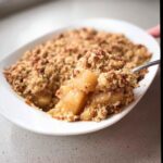 A spoonful of warm Gluten-Free Apple Crumble showing tender apples and crunchy topping.