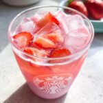 Close-up of a Starbucks Pink Drink Copycat made with ice, pink liquid, and fresh strawberry slices.