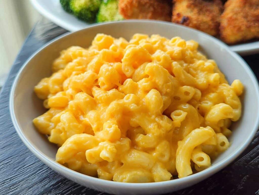 Close-up of a bowl filled with creamy, bright orange Gluten-Free Mac and Cheese (Stovetop) made with elbow macaroni.