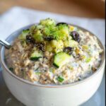 Close-up of Veggie-Packed Savory Overnight Oats topped with cucumber, olives, and dill.